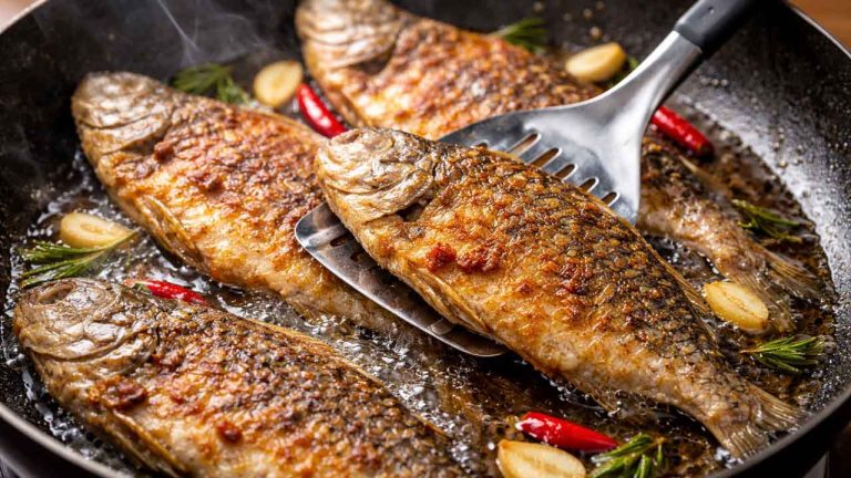 Người dùng kẹp gắp cho cá đã làm sạch vào chảo dầu nóng để chiên cá không bị dính chảo