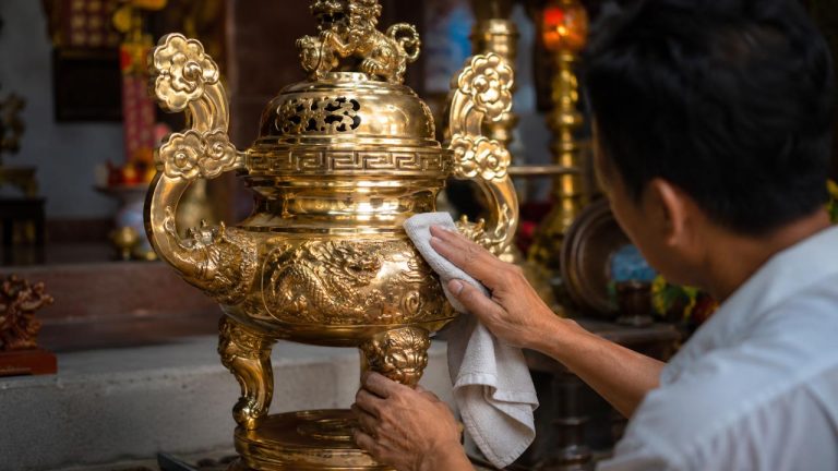 Một người đang lau chùi lư đồng sáng bóng tại nhà