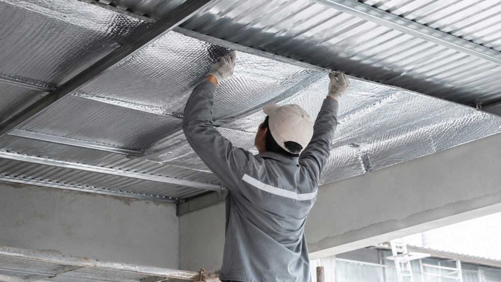 Công nhân lắp đặt tấm cách nhiệt dưới mái tôn để giảm nhiệt